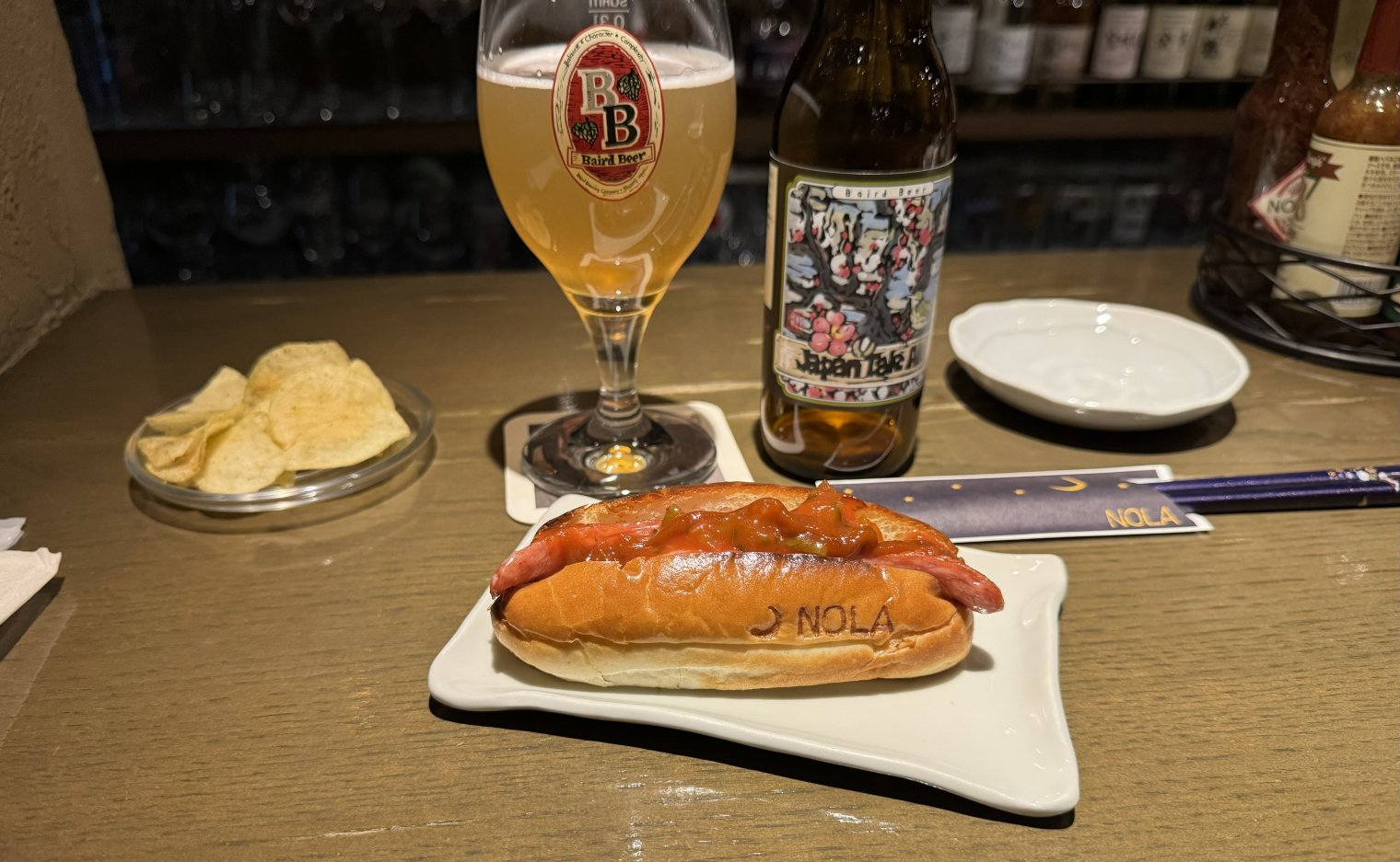 A Japanese beer with chips and a chilli hot dog