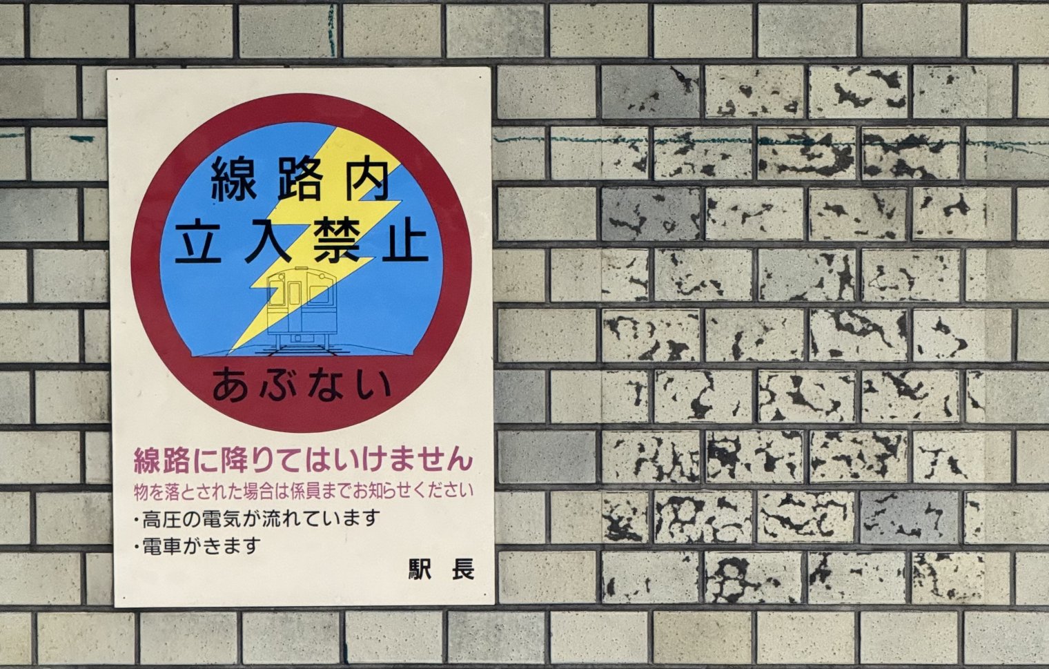 A warning sign on the wall of a subway in Osaka, next to the remnants of another sign that was removed at some point in the last 50 years