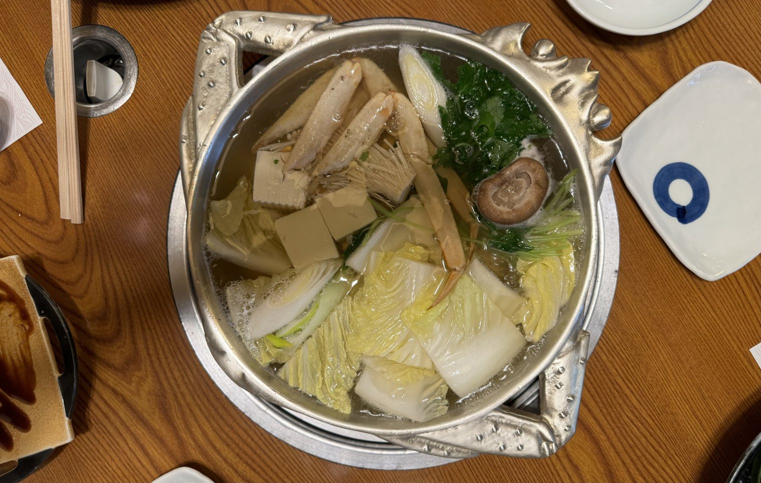A pot of crab and assorted vegetables cooking in a light broth at a king crab restaurant in Osaka