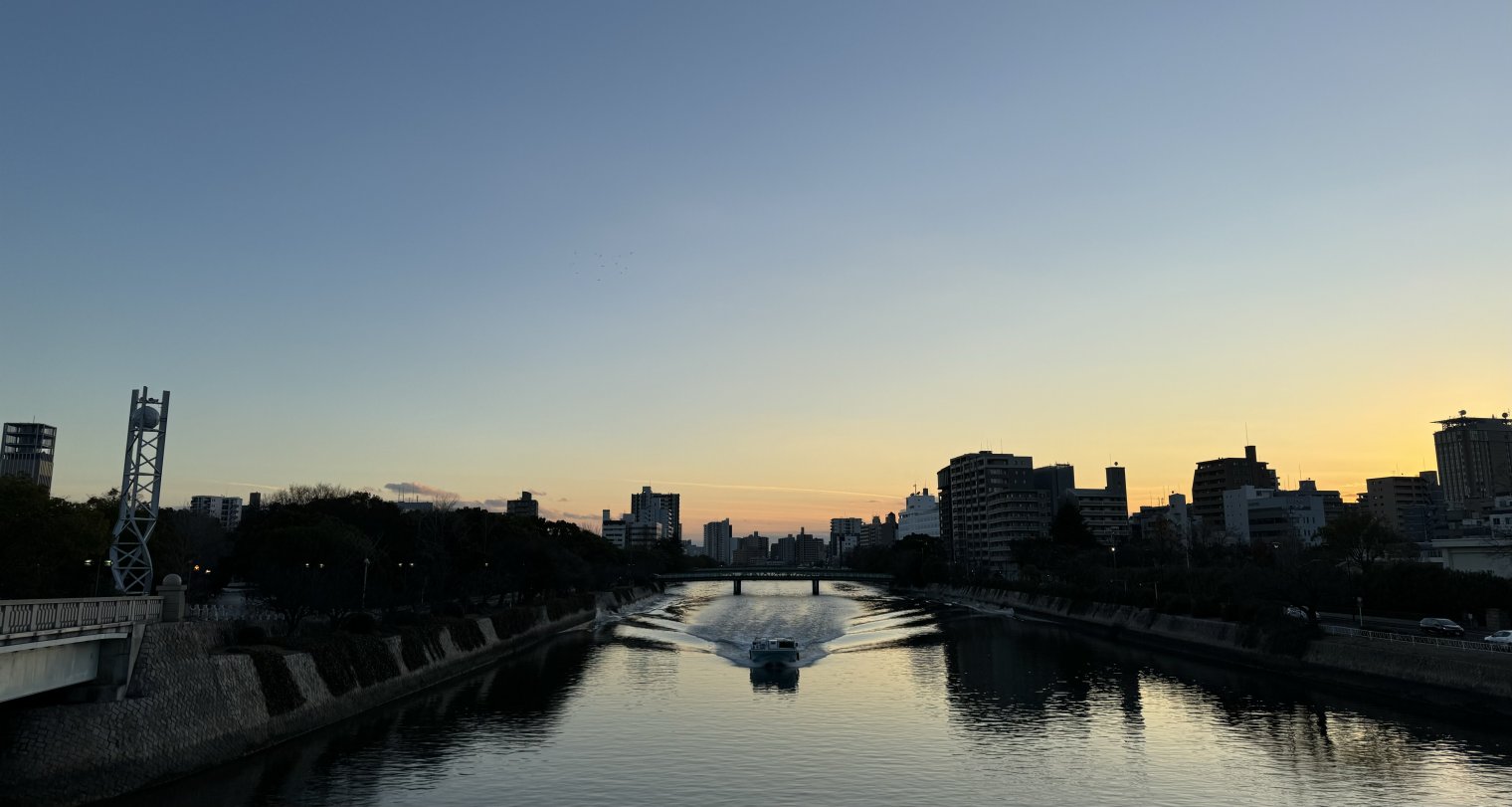 Sunset overlooking riverway near Hiroshima Peace Park, with a ferry travelling towards the camera