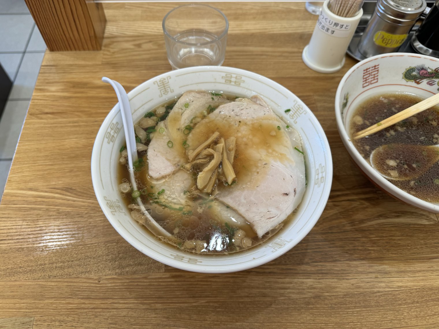 A full bowl of shouyu ramen next to a mostly consumed one in Onomichi