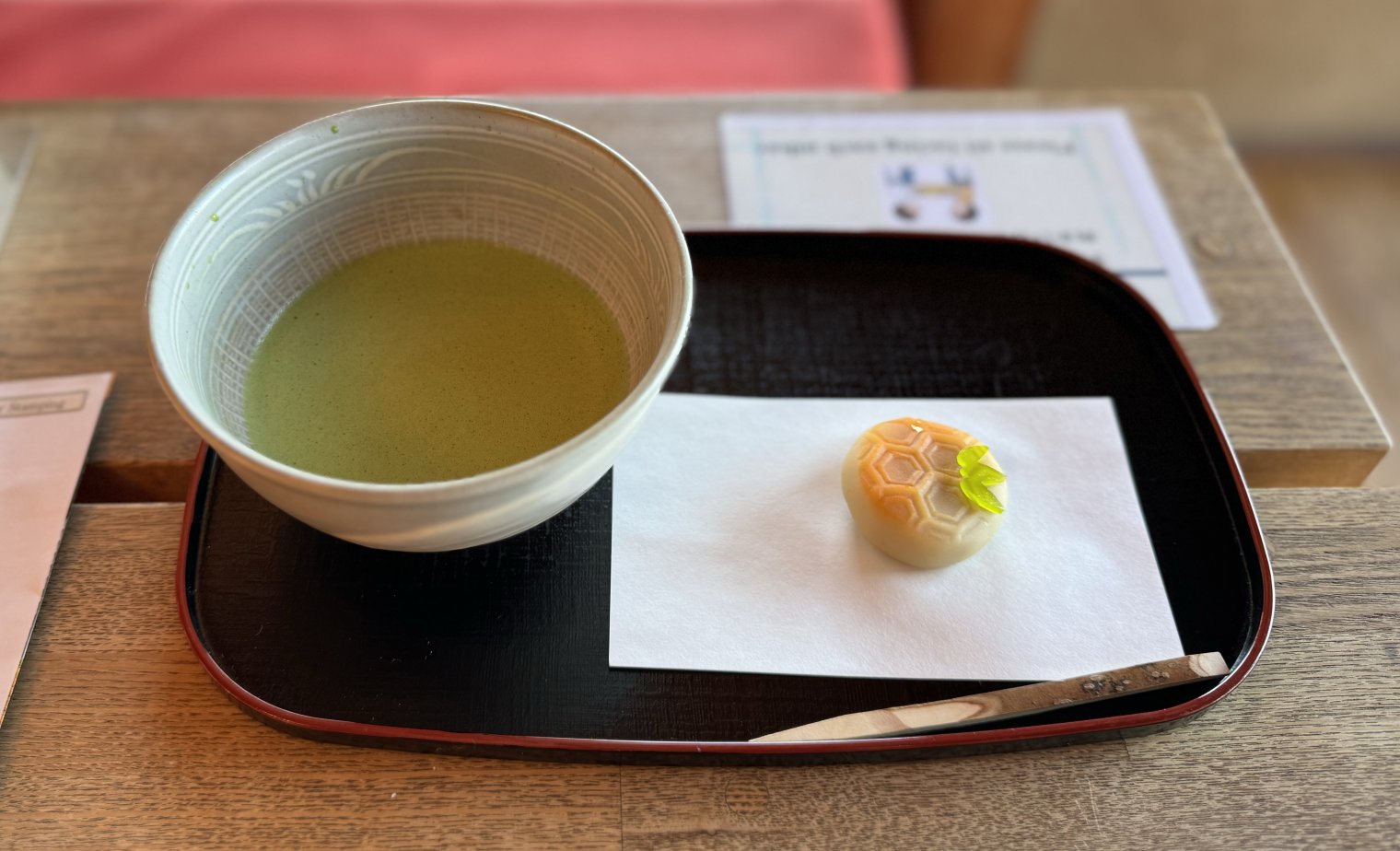 Bowl of matcha tea with mochi treat beside it